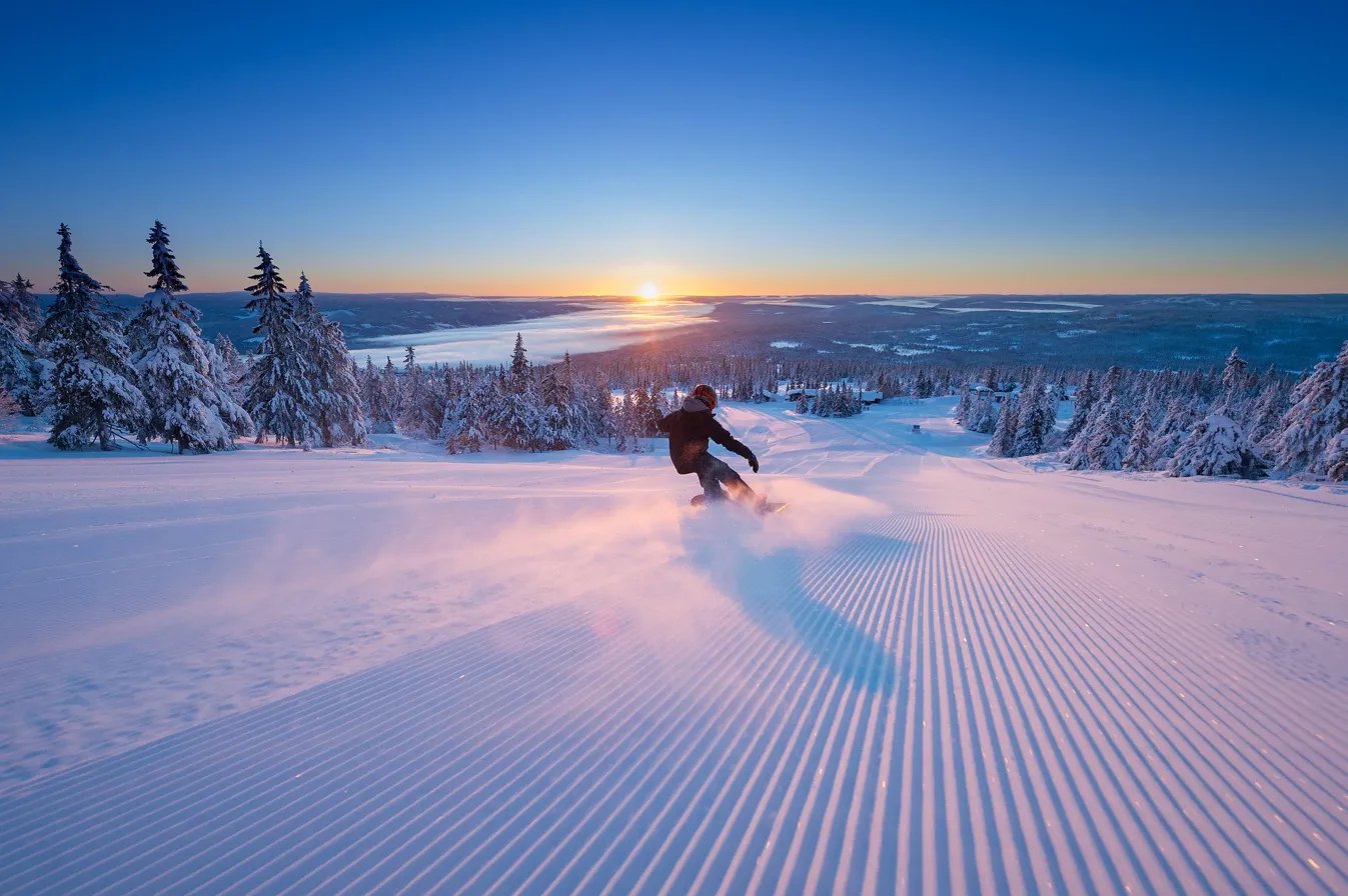 A skier carving fresh corduroy at sunrise