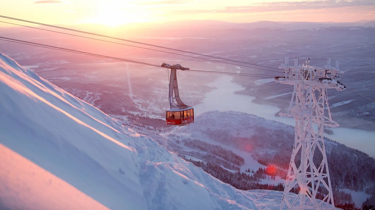 A gondola rising over the mountains at sunset