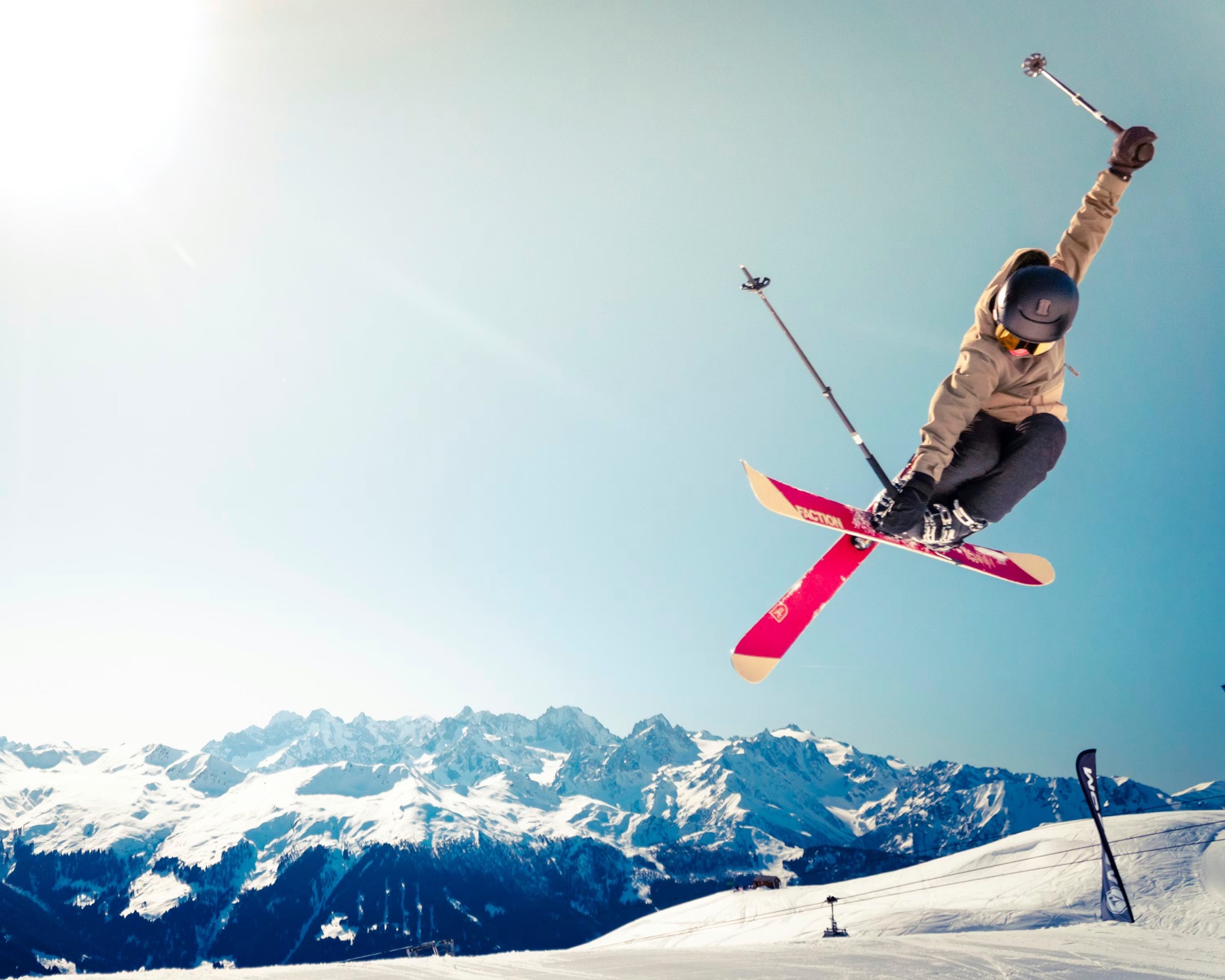 A skier soaring above the Alps under a clear sky